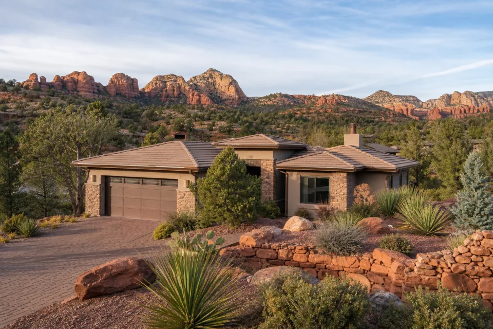 A high-desert home surrounded by natural stone, juniper, and red-rock terrain.